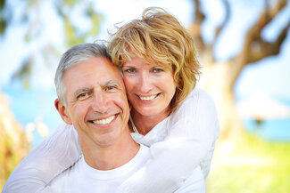 mature couple smiling outdoors near beach dental implants Nashua, NH